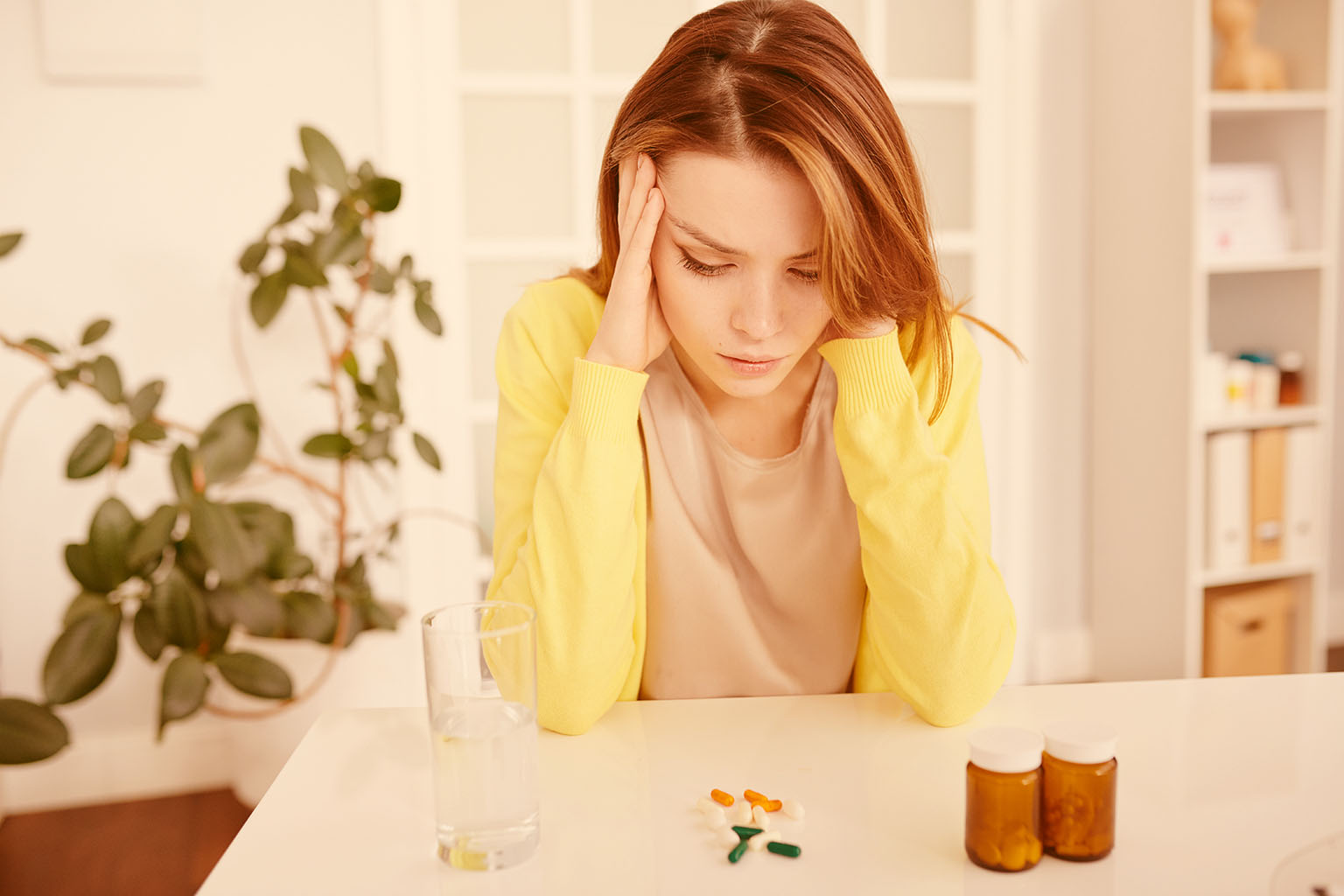 Portrait of anxious young woman sitting at desk in doctors office and waiting for doctor